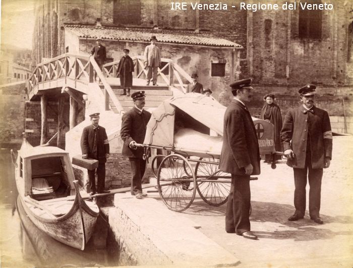 Venezia - Vita veneziana e lagunare - Attività pubbliche - Assistenza e Sanità - Croce Azzurra - Prove di trasporto malati per via acqua - Persone - Portantini - Ragazzo in carozzino-barella - Gondola-ambulanza  di Filippi, Tomaso (fine/ inizio XIX/ XX)