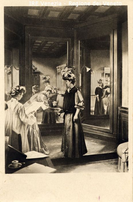 Venezia - Vita veneziana e lagunare - Attività pubbliche - Istruzione - Scuole - Scuola Professionale Femminile per il Commercio a S. Provolo - Corsi di economia domestica - Sala di prova - Allieve del corso di sartoria - Modella allo specchio  di Filippi, Tomaso (primo quarto XX)