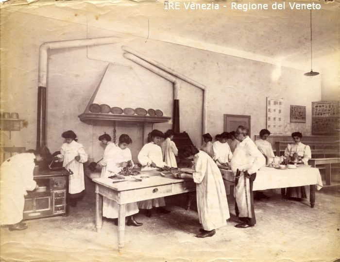 Venezia - Vita veneziana e lagunare - Attività pubbliche - Istruzione - Scuole - Scuola Professionale Femminile per il Commercio a S. Provolo - Corsi di economia domestica - Aula di cucina - Allieve che cucinano - Insegnante  di Filippi, Tomaso (fine/ inizio XIX/ XX)