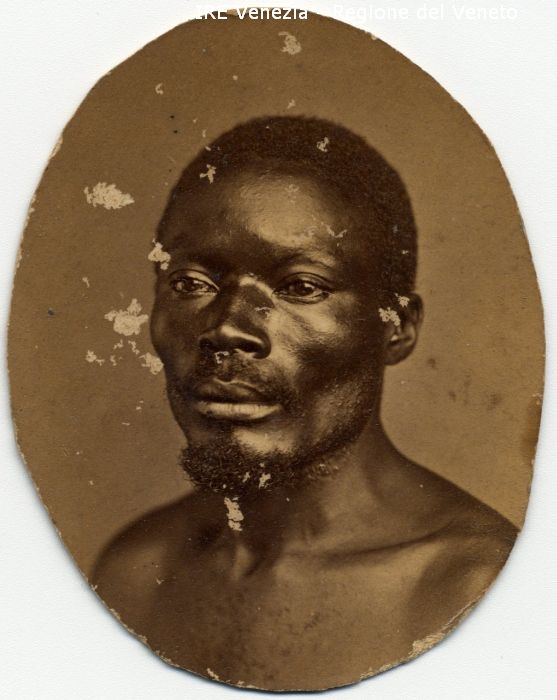 Ritratti: in studio; mezzo busto; in semi profilo - Uomo: con baffi e pizzo; di razza africana - Sfondo  di Naya, Carlo (seconda metà XIX)